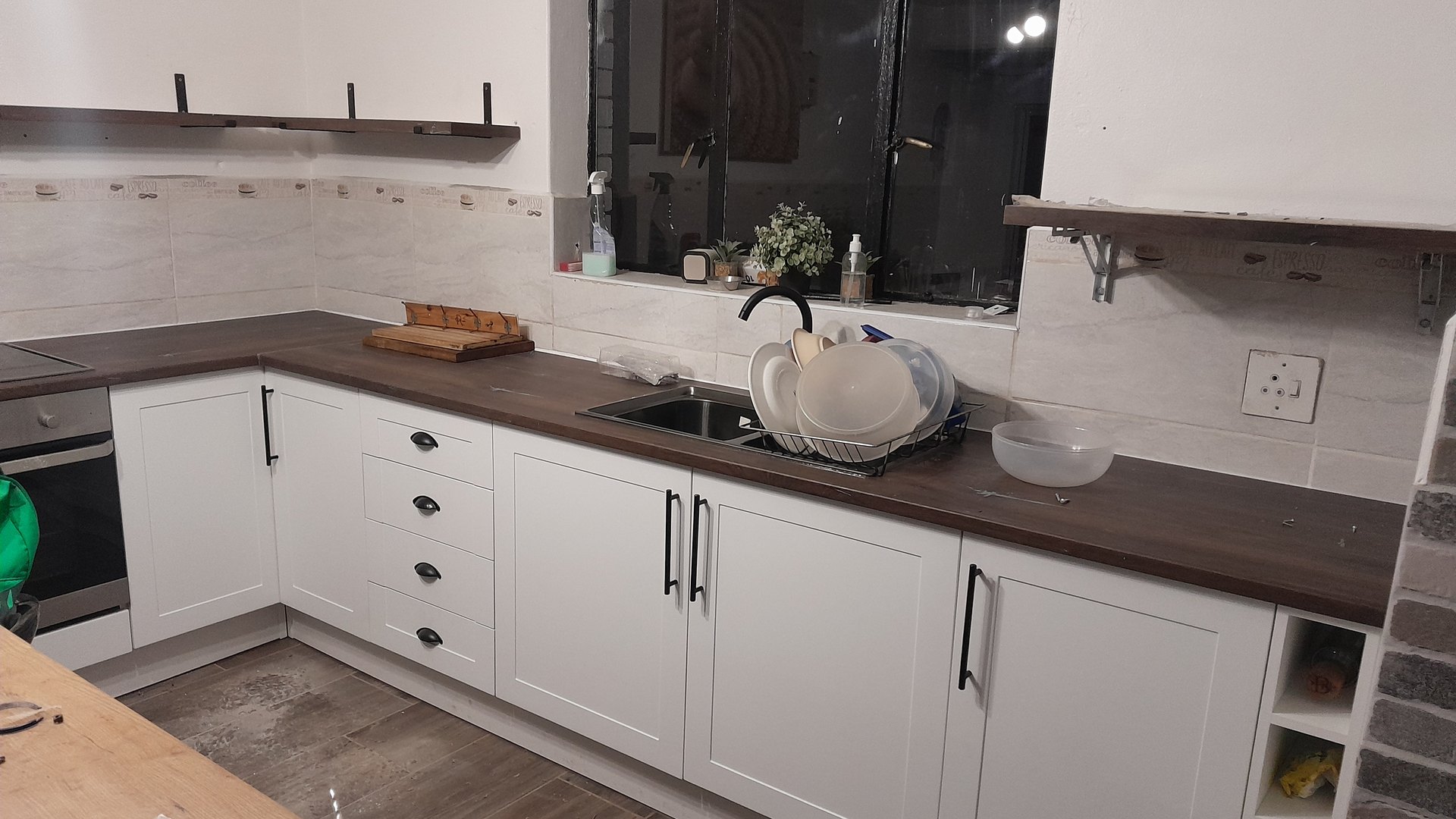 Fitted white kitchen with a timber counter and natural light