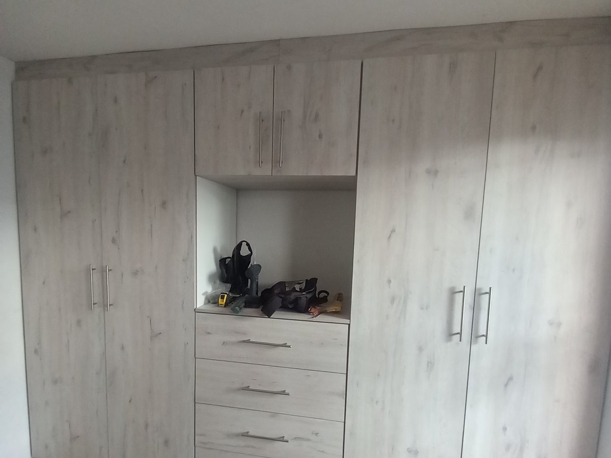Timber-tone fitted wardrobe running the length of a bedroom wall