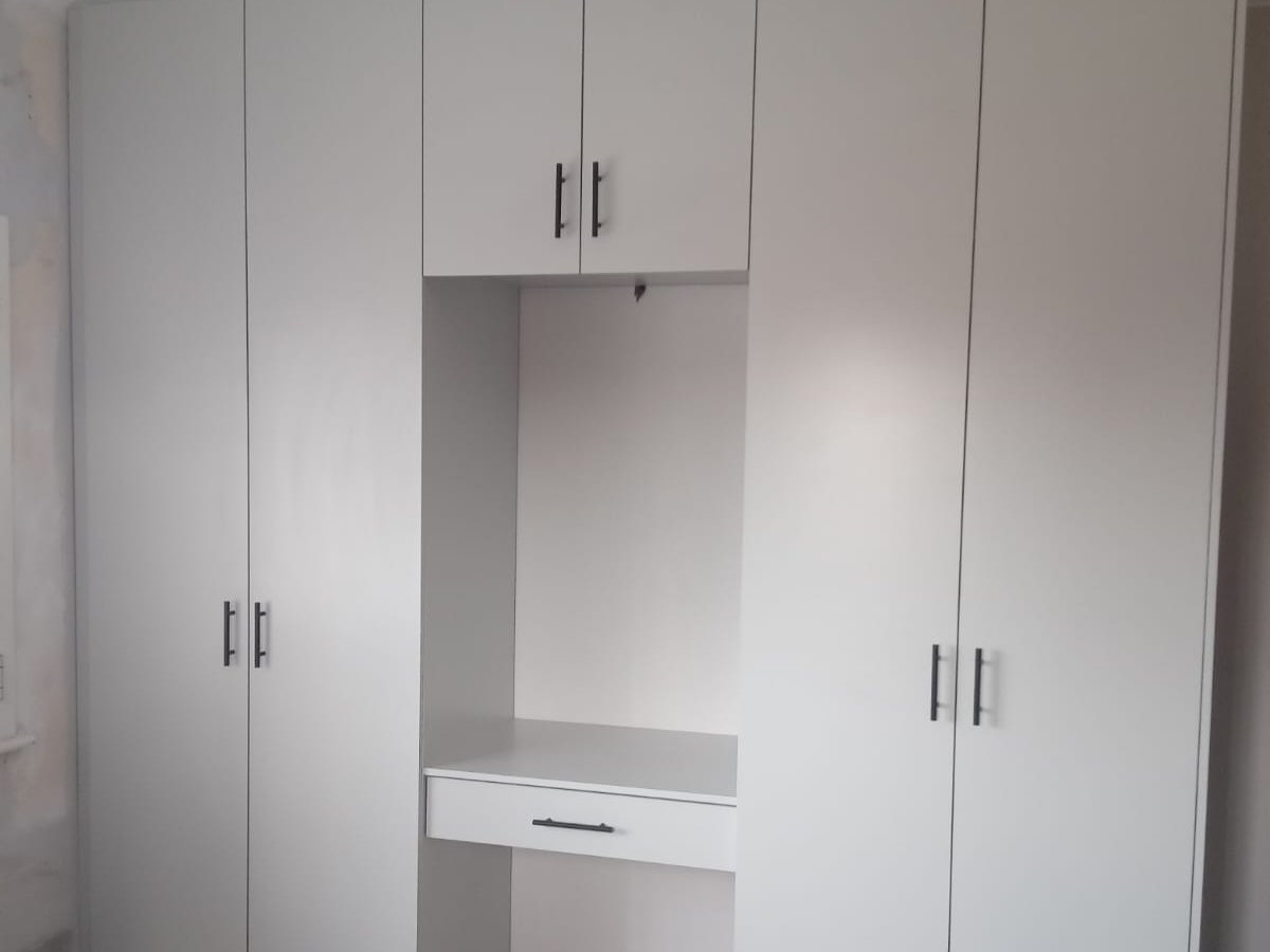 White built-in wardrobes with a central open section