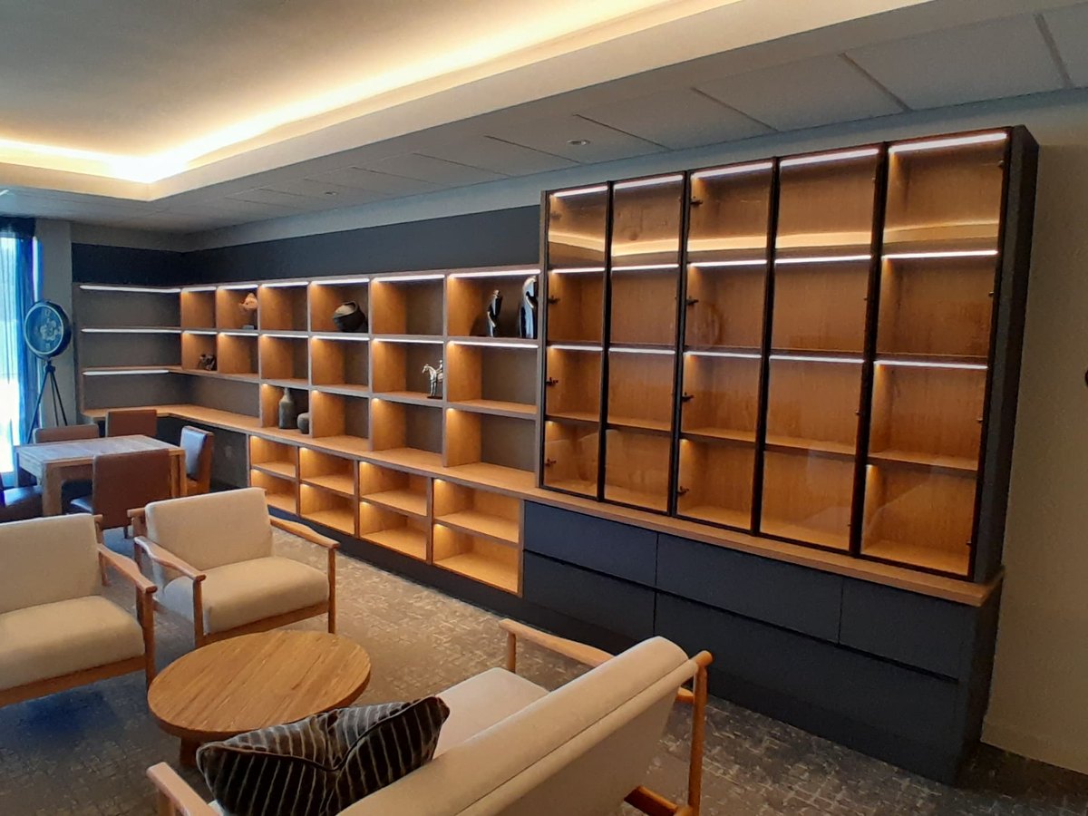 Timber shelving wall with concealed lighting and seating