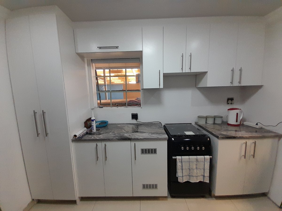 Fitted white kitchen with a window and floor-to-ceiling storage