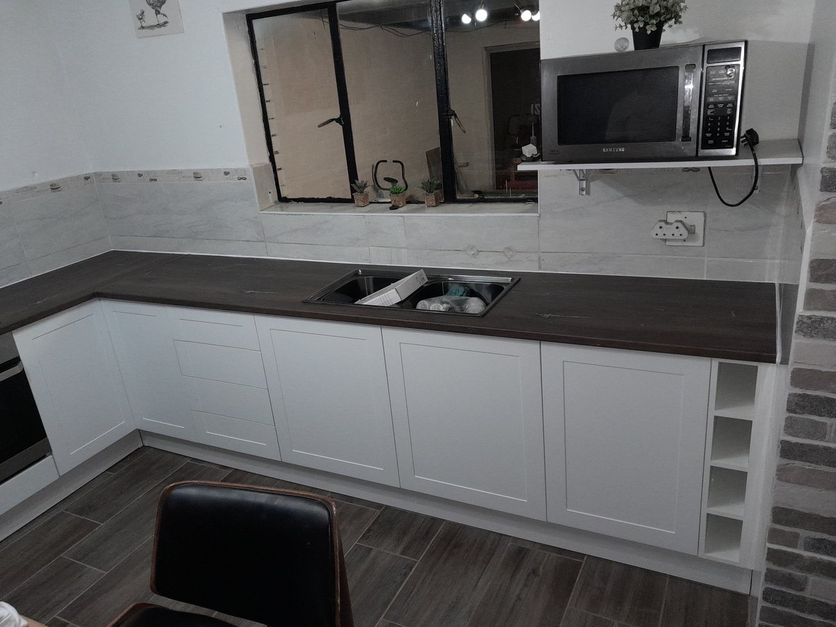 Fitted kitchen with a dark counter, shelving and extractor
