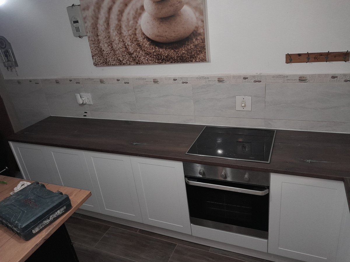 White fitted kitchen run with a timber-tone counter