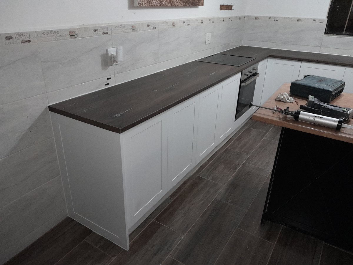 Long kitchen run in white with a dark counter and oven housing