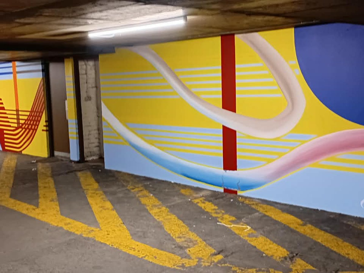 Painted mural and bay markings across a parking garage wall